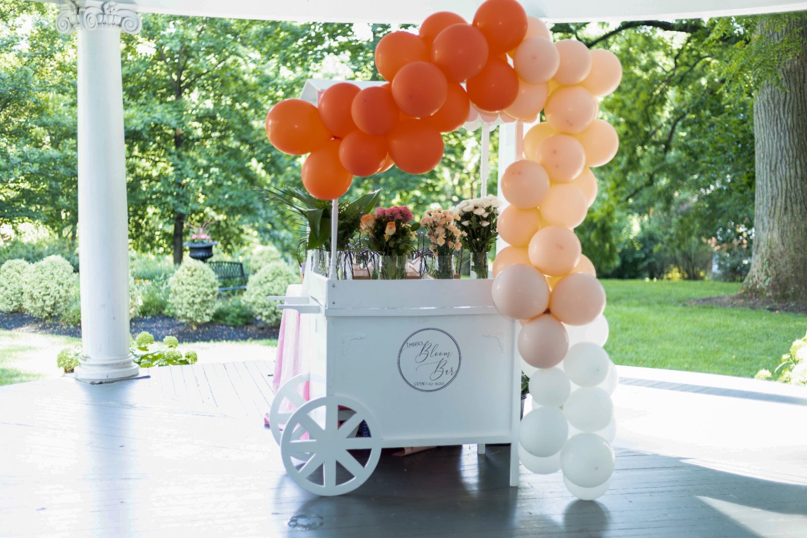 White flower cart with balloon garland in a garden