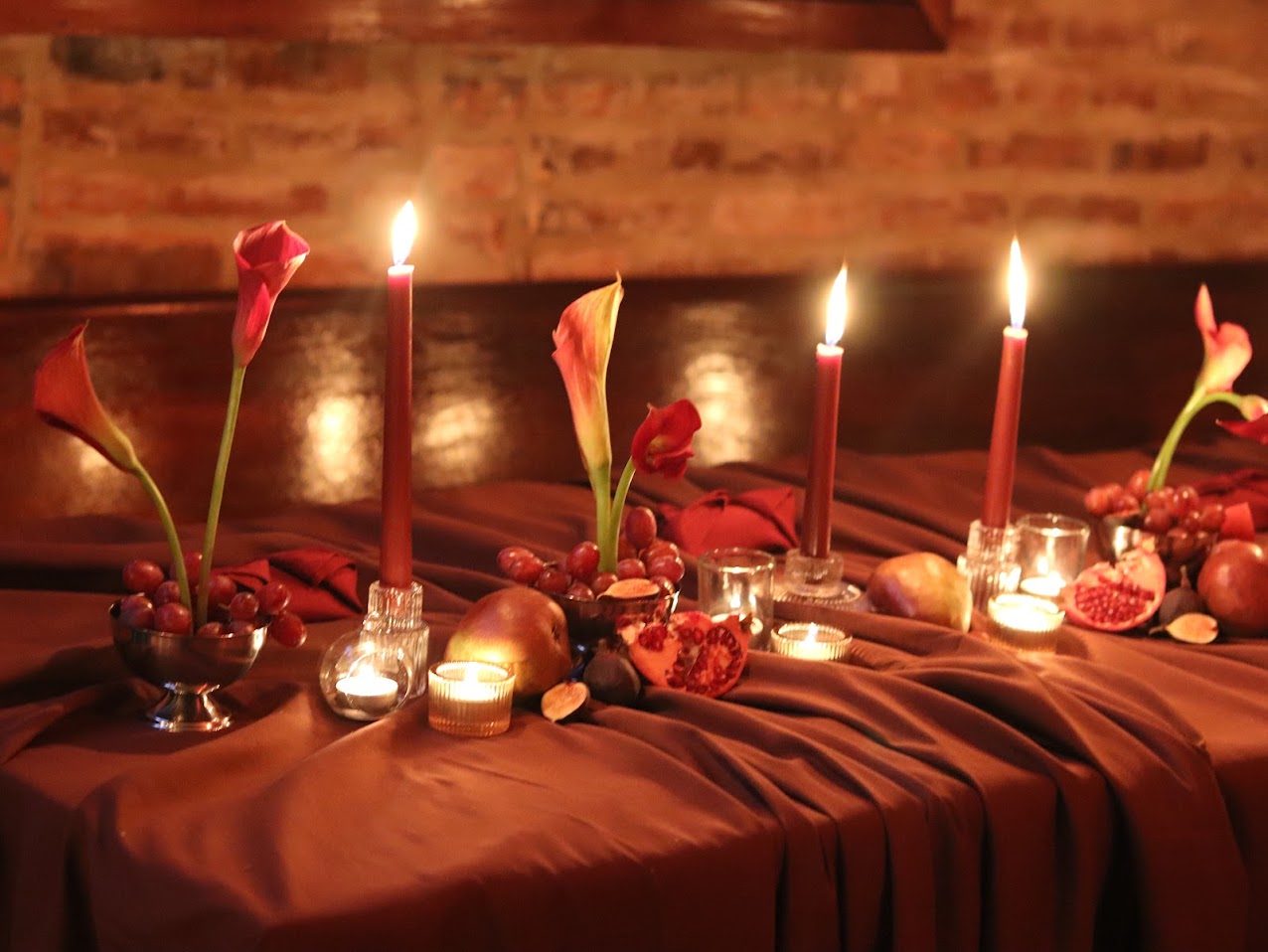 Candlelit crimson tablescape with calla lilies and fruit